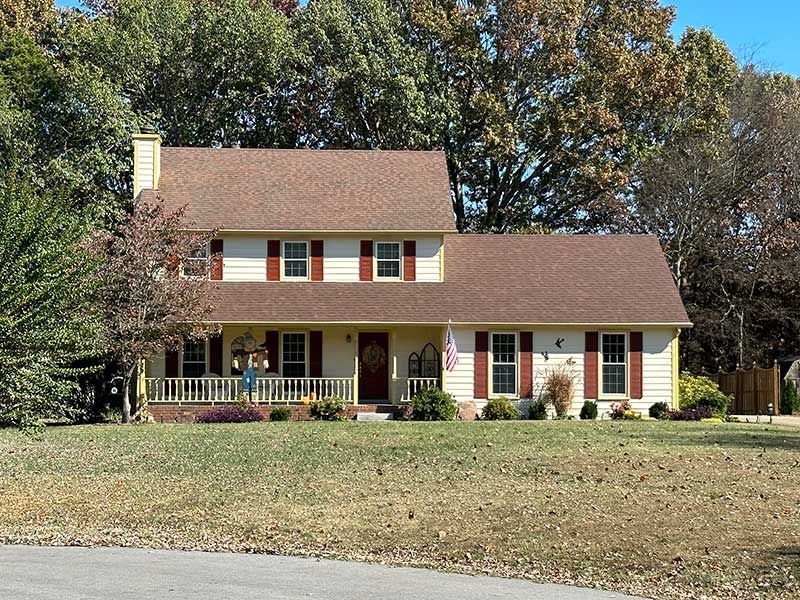 A white house with a brown roof and red shutters