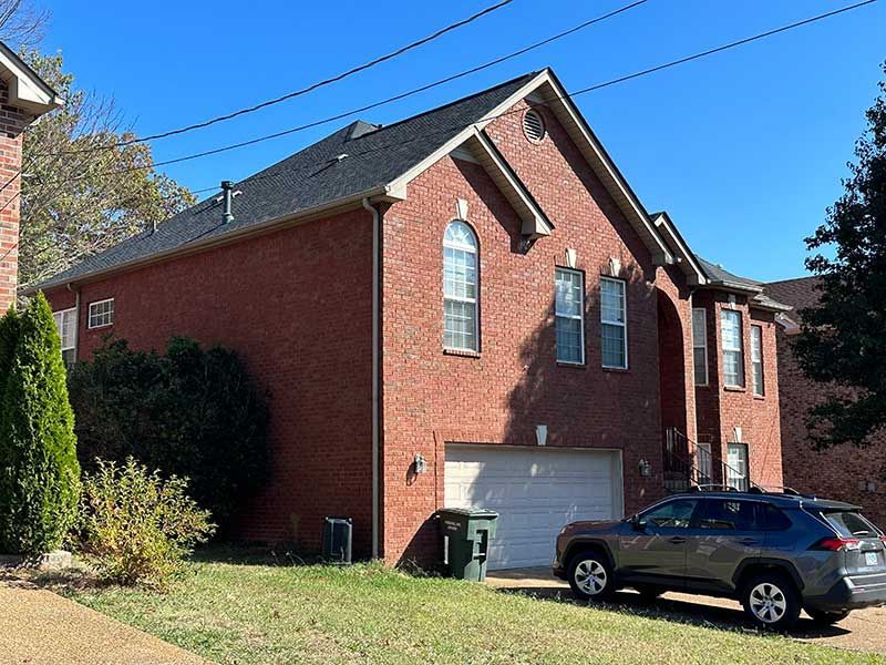 A brick house with a car parked in front of it.