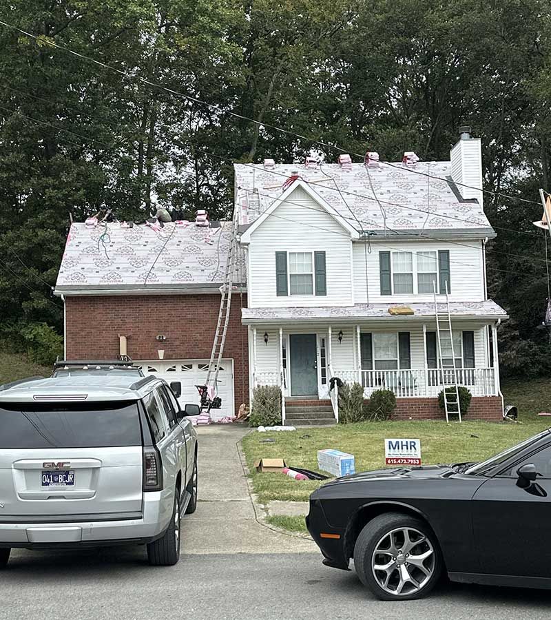 A black car is parked in front of a white house.