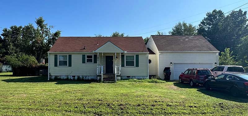 A white house with a red roof is sitting on top of a lush green field.