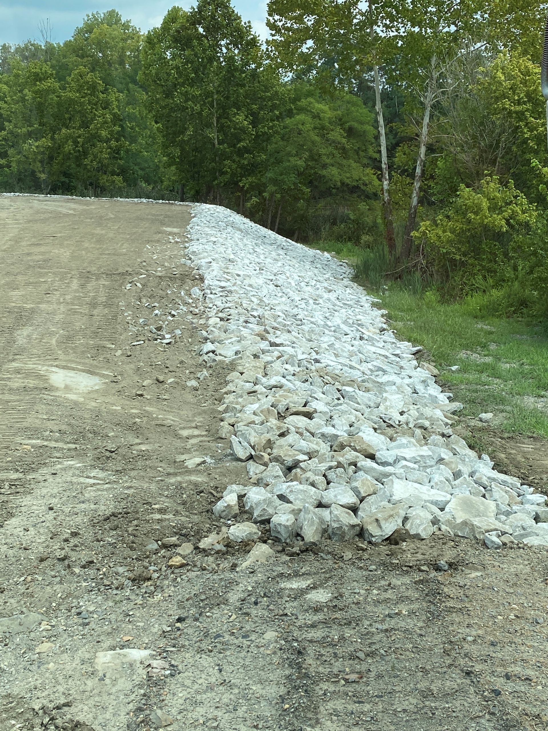 A pile of rocks is sitting on the side of a dirt road.