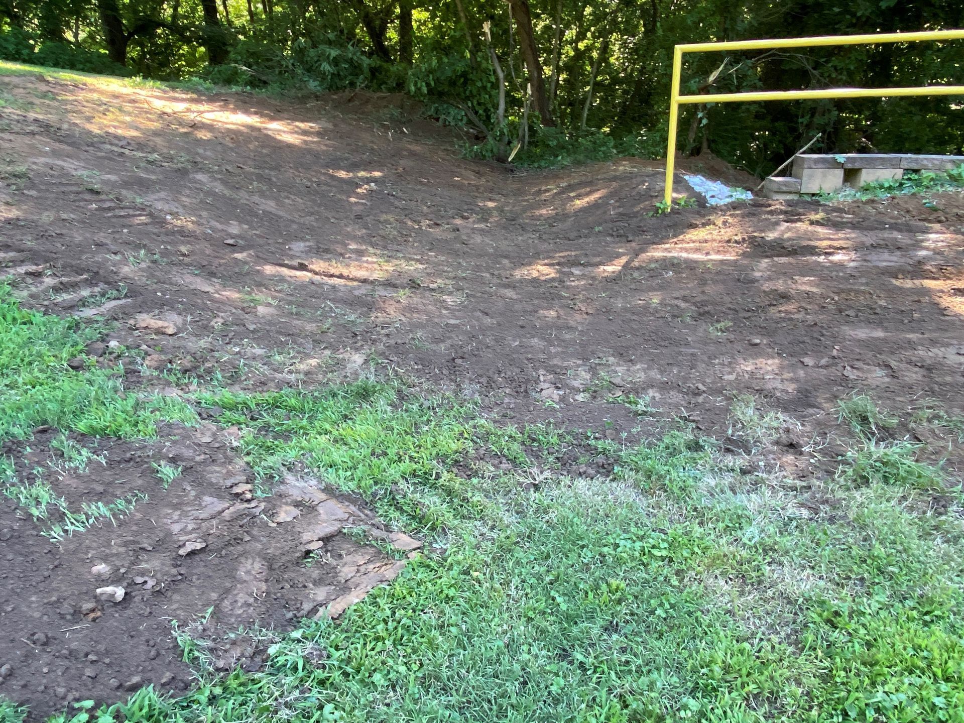 A dirt road with a yellow railing on the side of it.