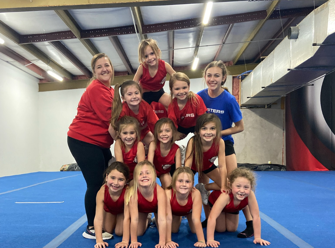 A group of young girls are posing for a picture in a gym.