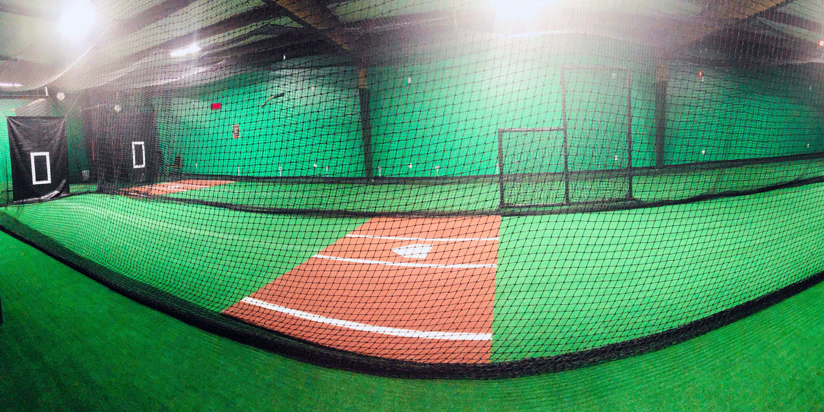 A baseball cage with a baseball field inside of it.