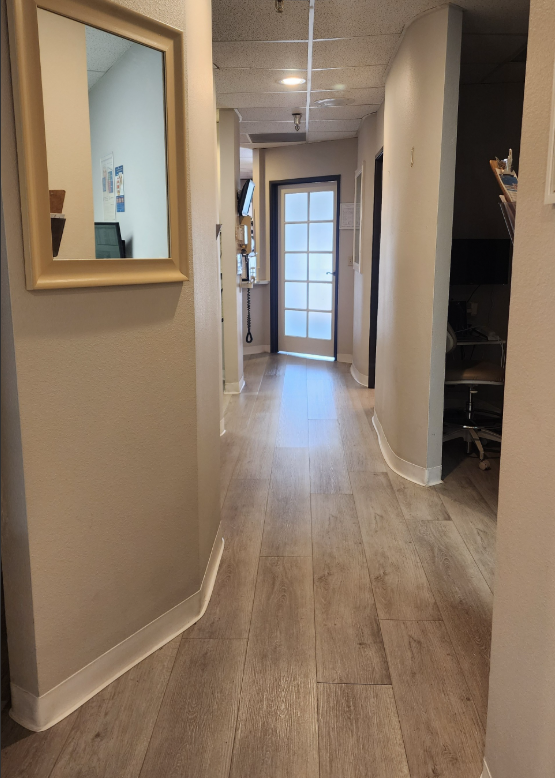 A hallway with hardwood floors and a mirror on the wall