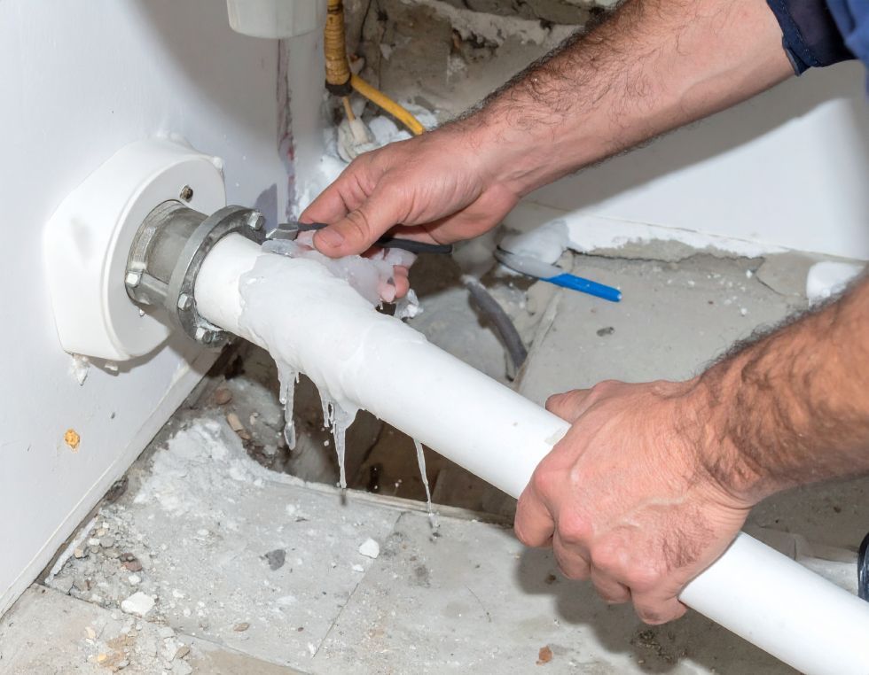 A person connecting a white pipe to a water heater, working in a utility area.