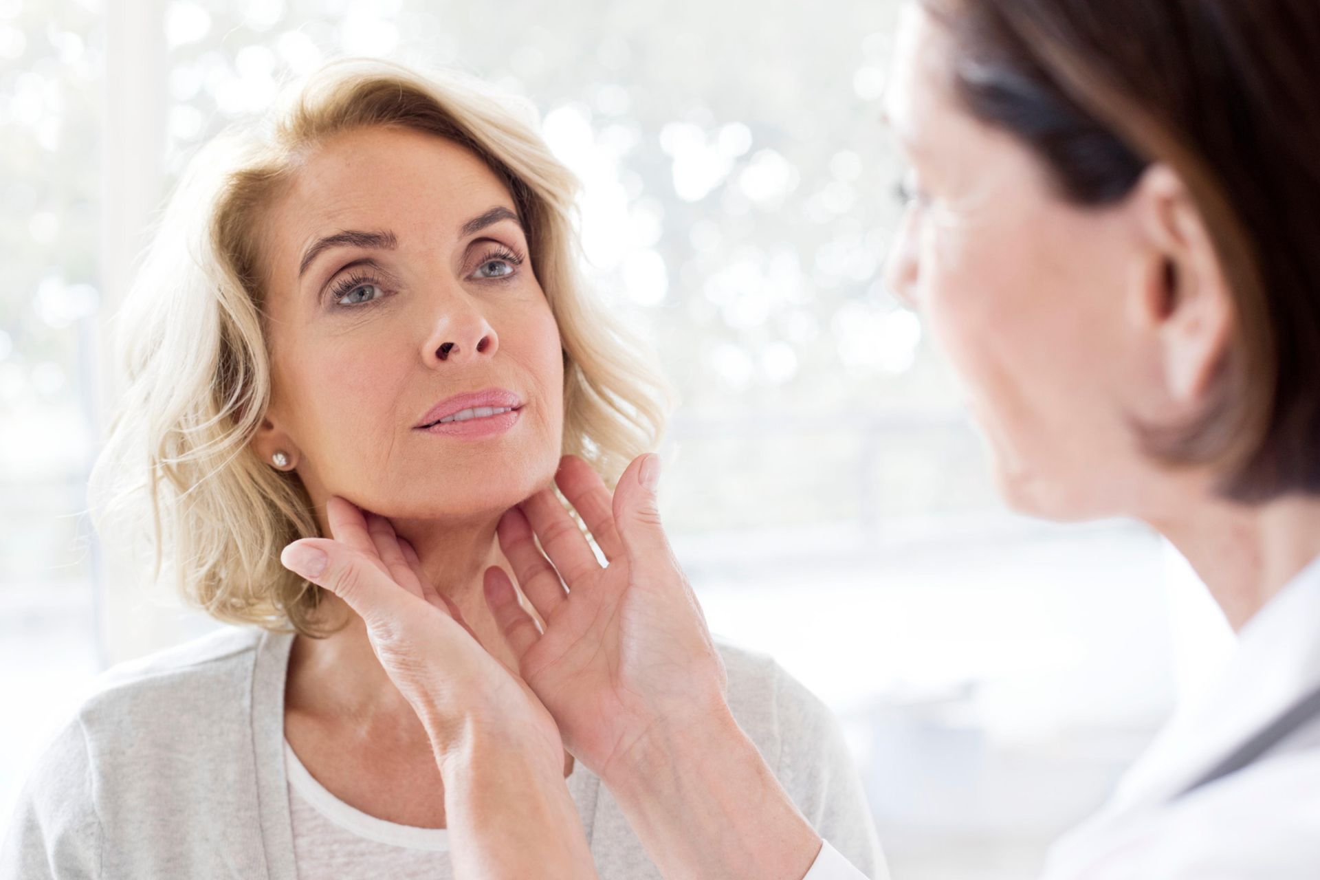 A woman is having her neck examined by a doctor.