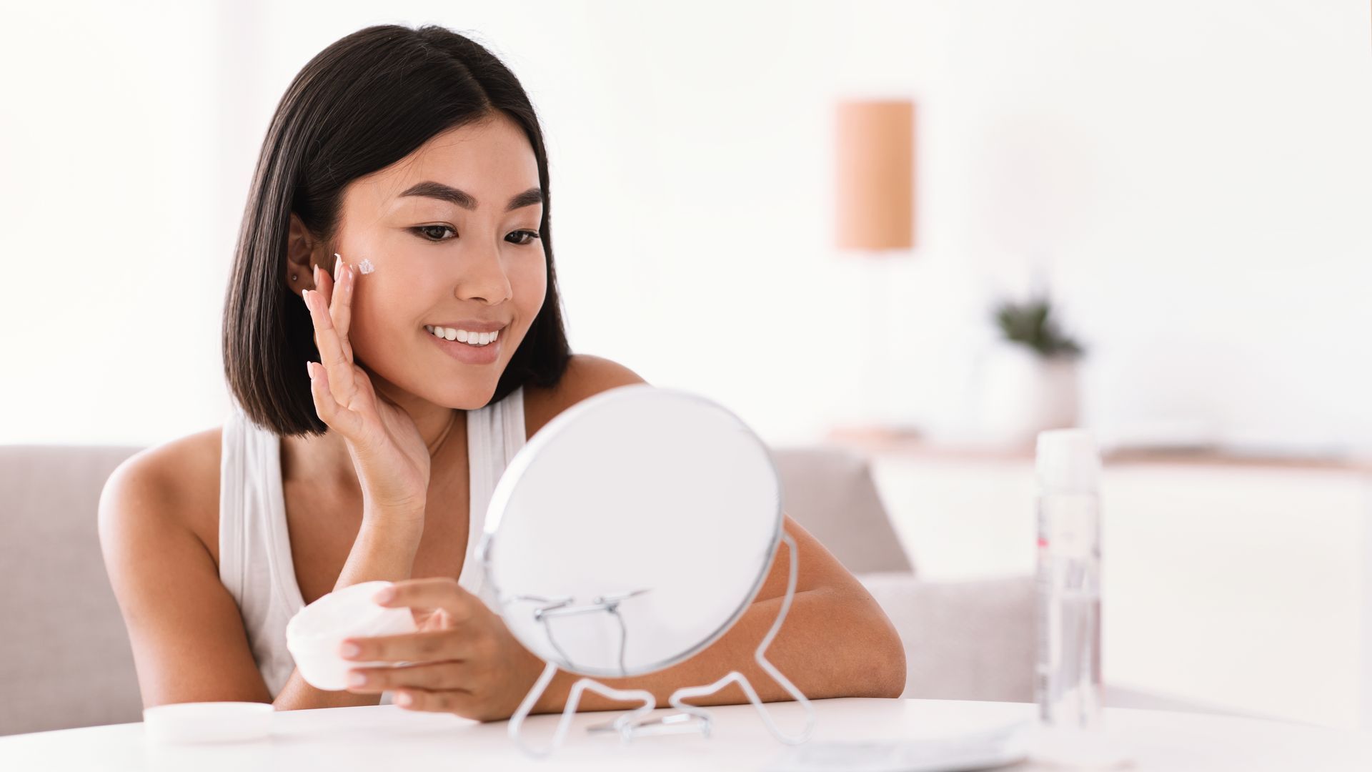 A woman is looking at her face in a mirror.