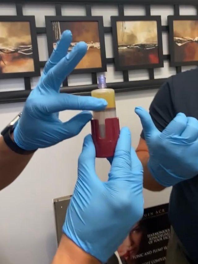 A person wearing blue gloves is holding a bottle