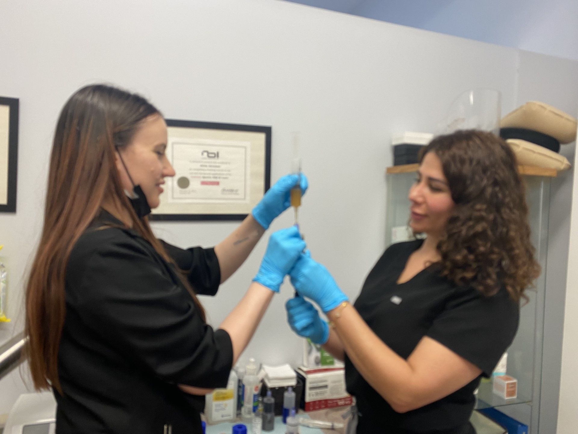 Two women are holding a syringe in their hands in a room.
