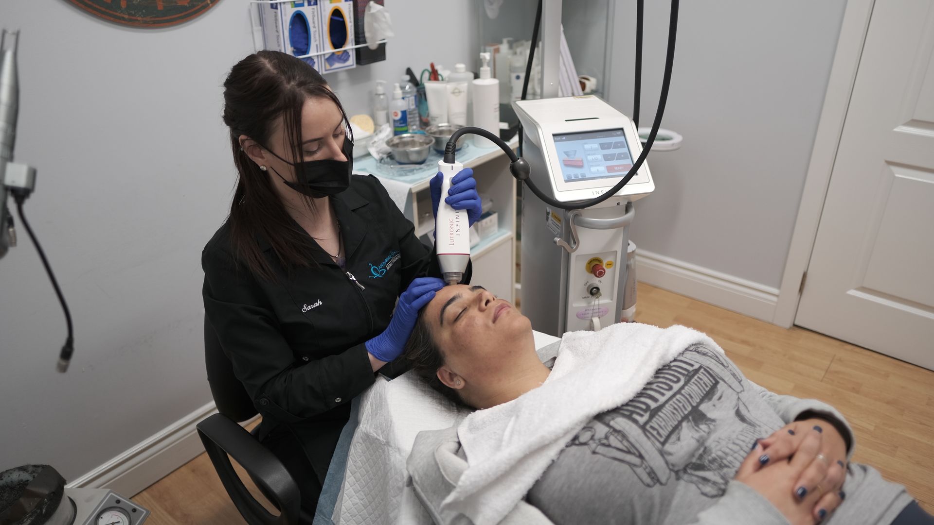 A woman is laying on a bed getting a treatment on her face.