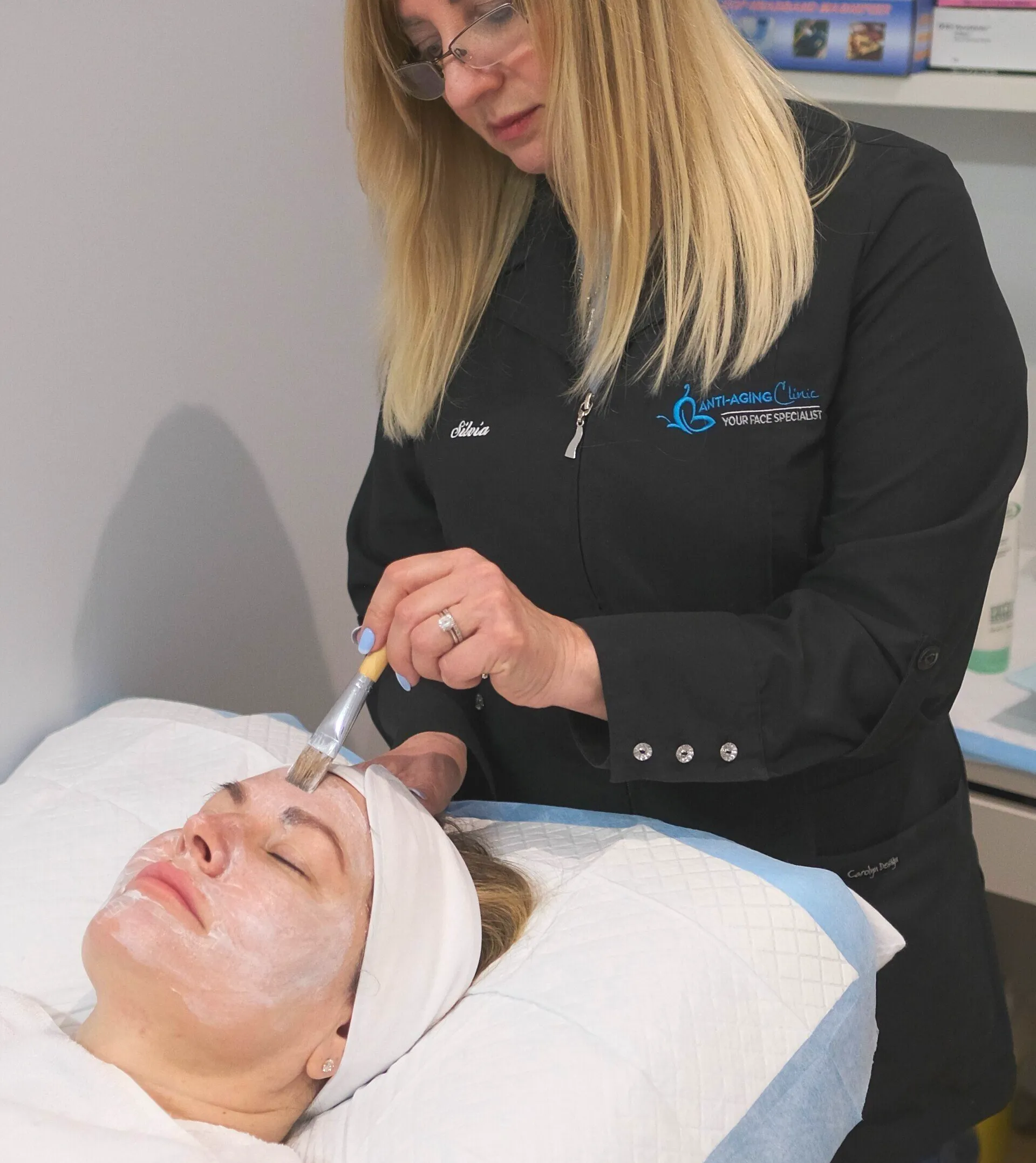 A woman is applying a cream to a woman 's face