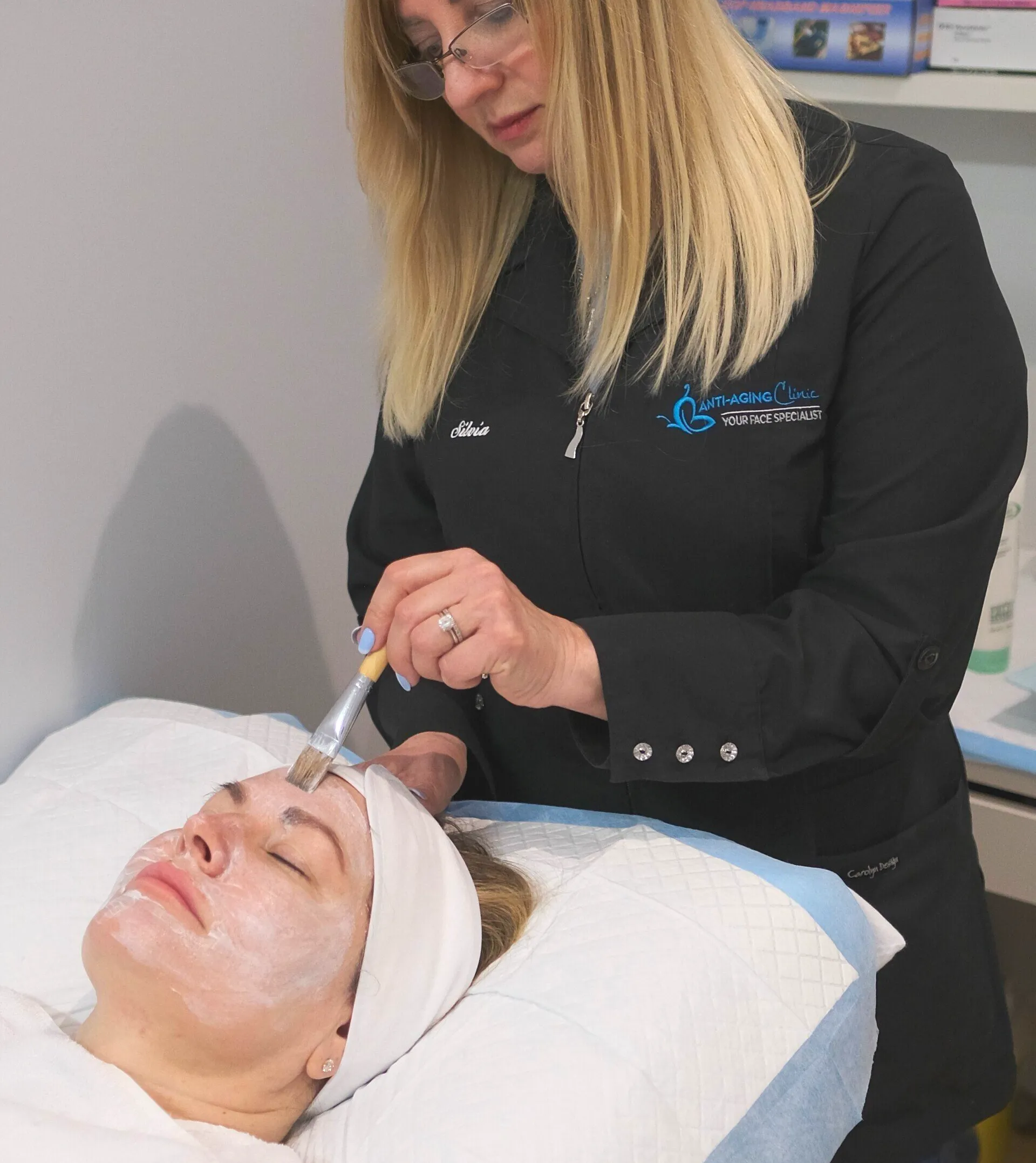 A woman is applying a mask to a woman 's face
