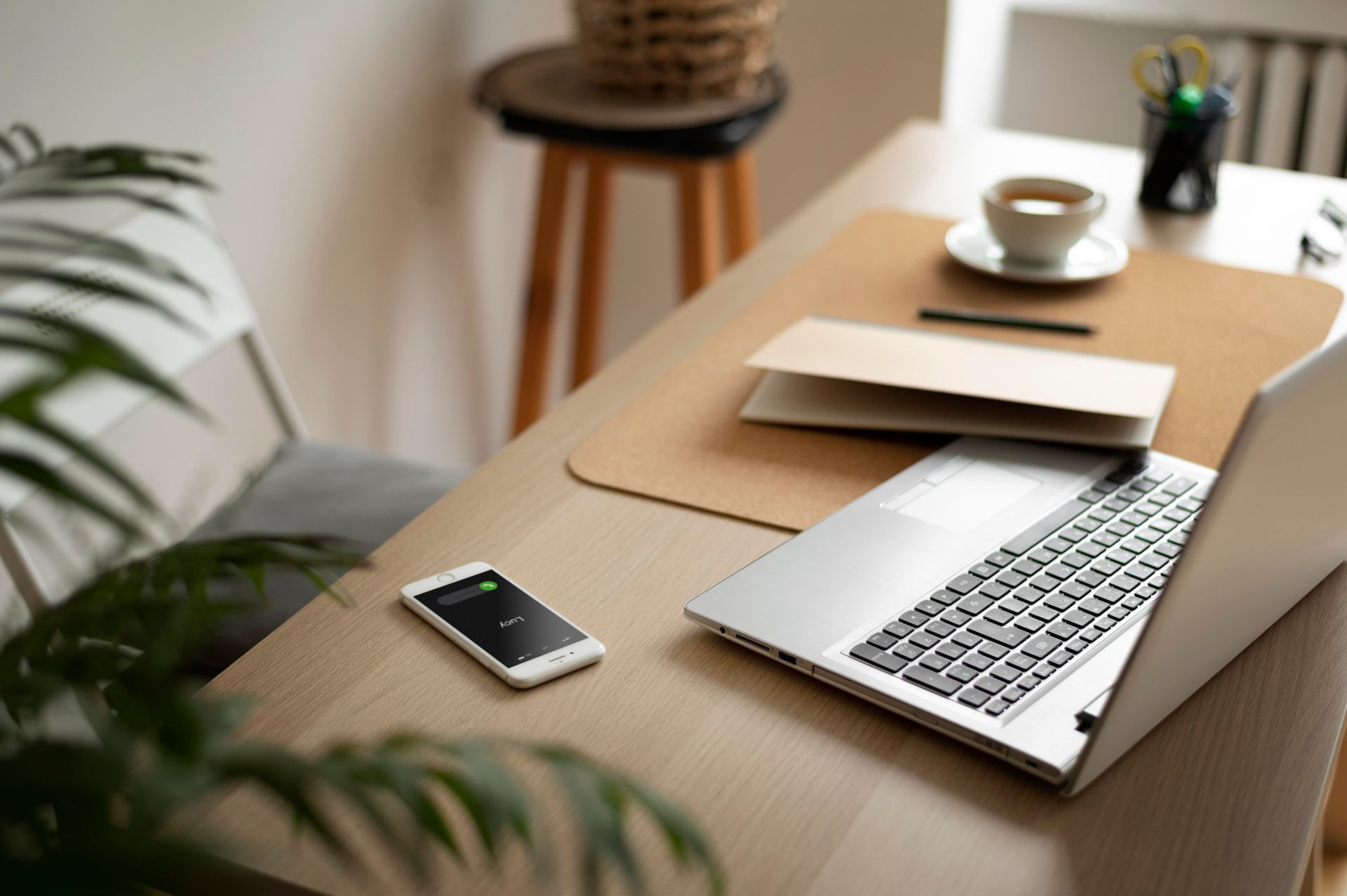 A laptop and a cell phone are on a wooden desk.