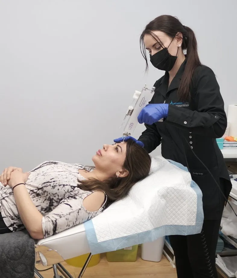 A woman wearing a mask is getting a mesotherapy treatment from a aesthetician