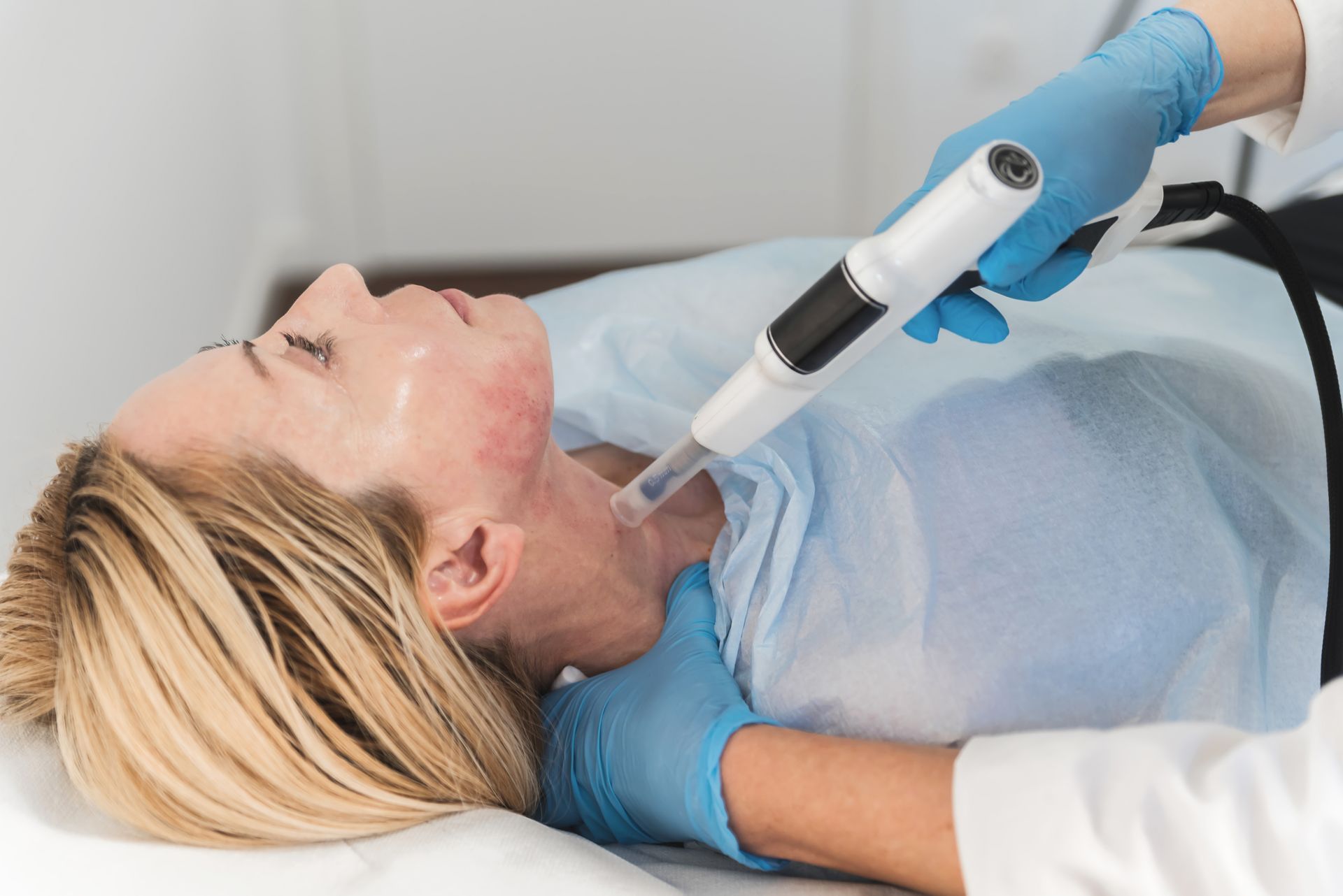 A woman is laying on a bed getting a facial treatment.
