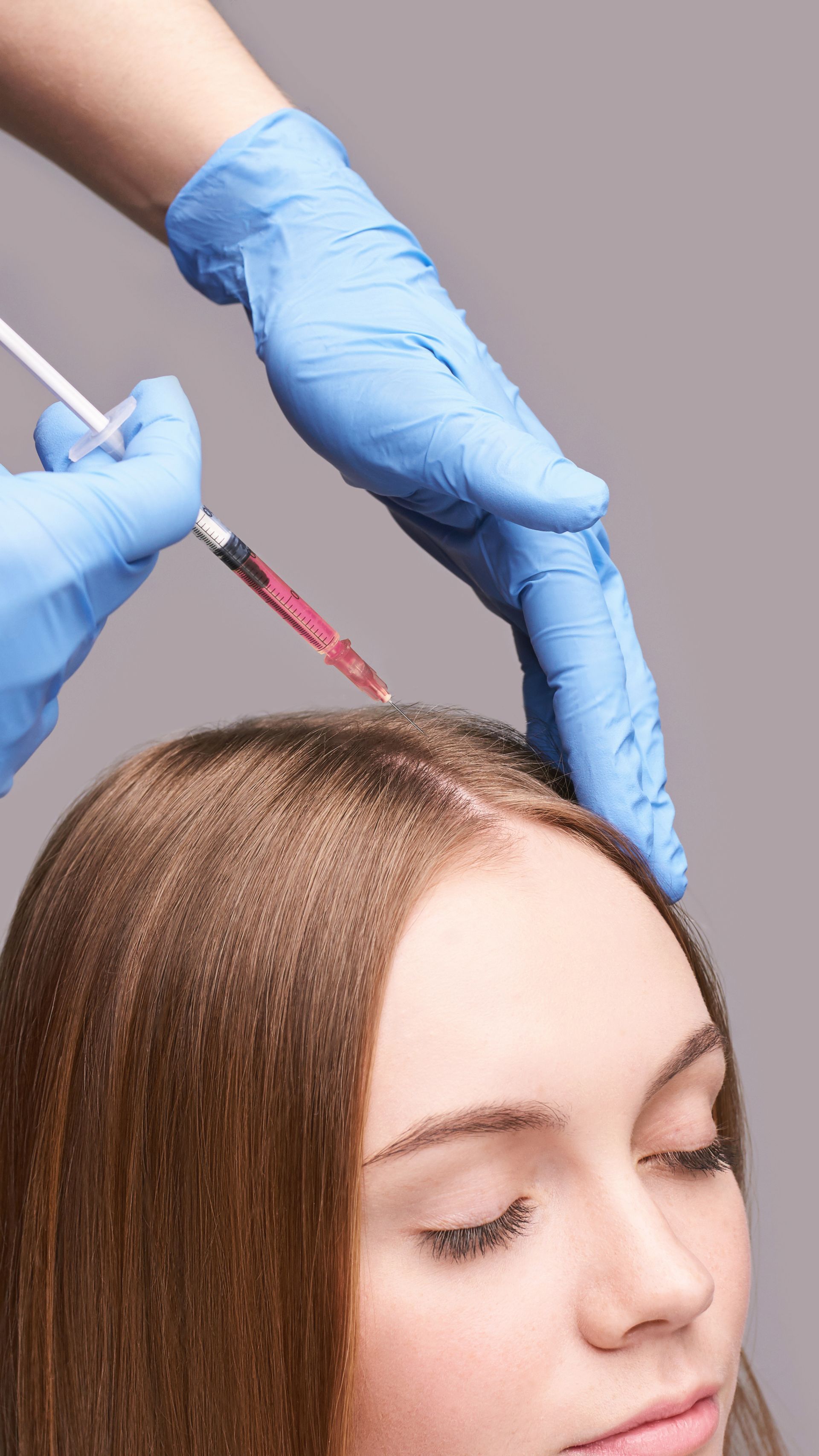 A woman is getting an injection in her hair.
