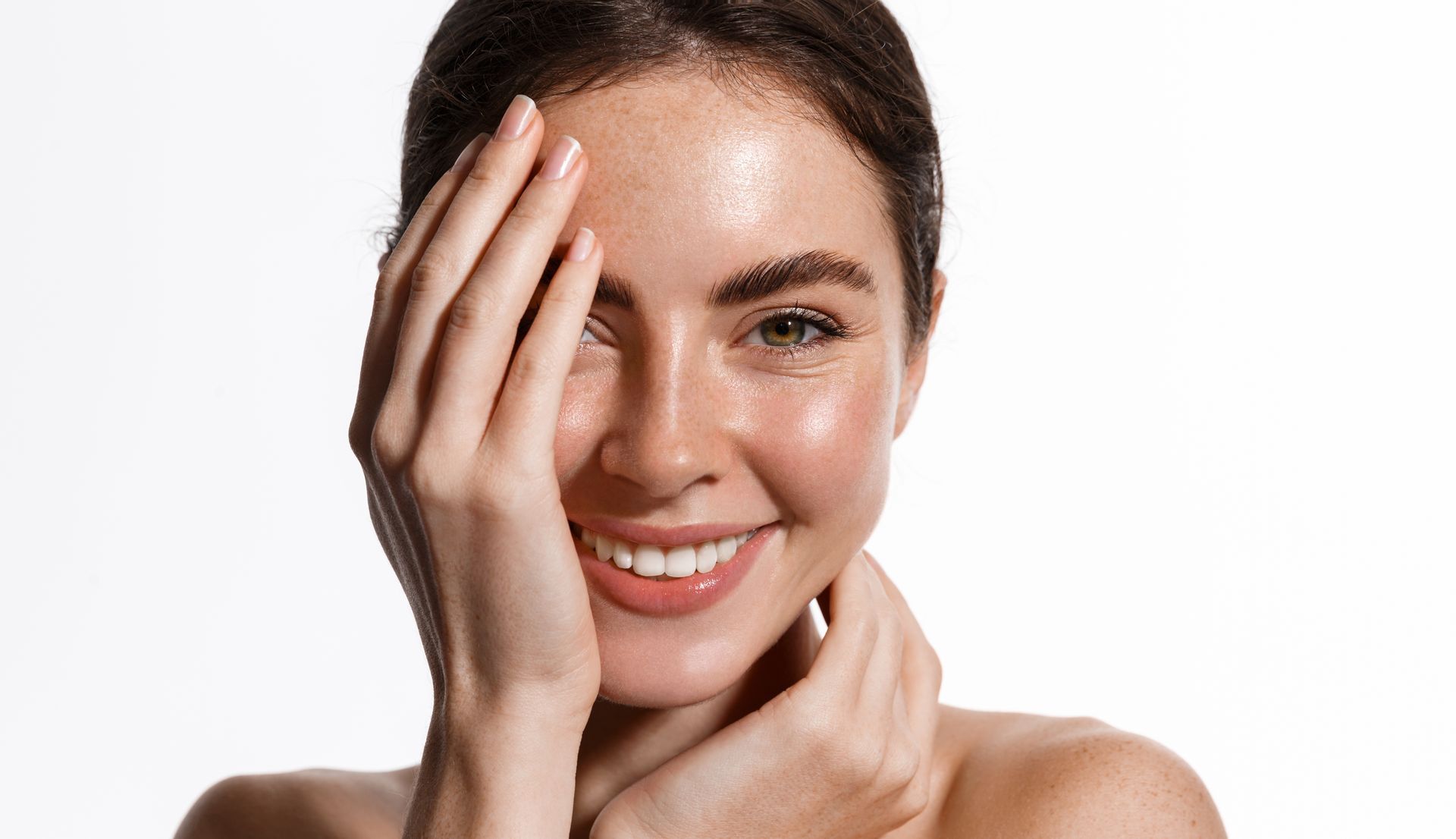 A woman is touching her face with her hand and smiling.