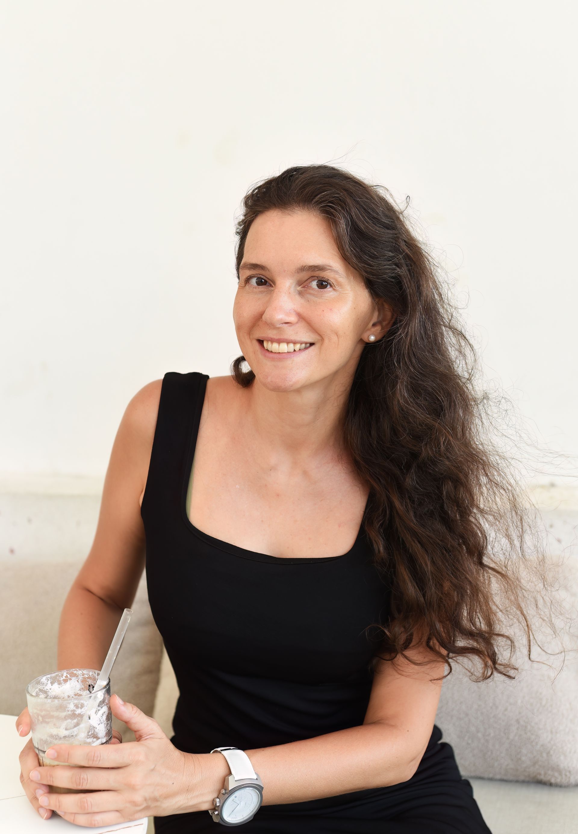 A woman is sitting on a couch holding a glass of water.