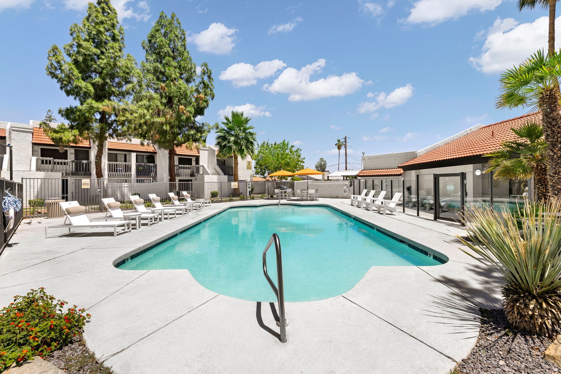 A large swimming pool surrounded by chairs and umbrellas in front of a building at Solei on West Thomas in Phoenix, AZ.