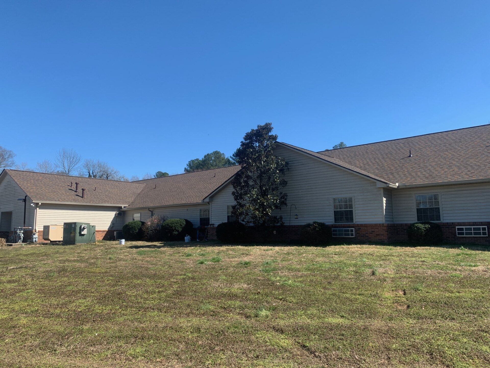 A house with a brown roof sits in the middle of a grassy field