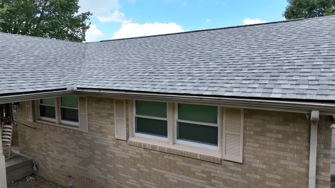 A brick house with a roof and two windows.