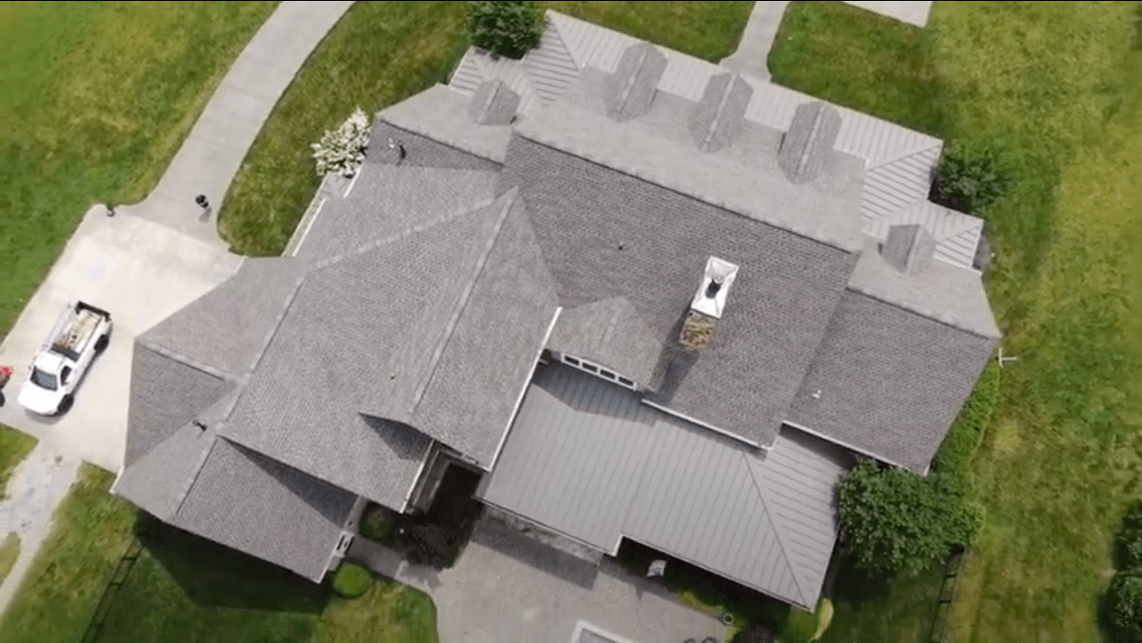An aerial view of a large house with a white truck parked in front of it.