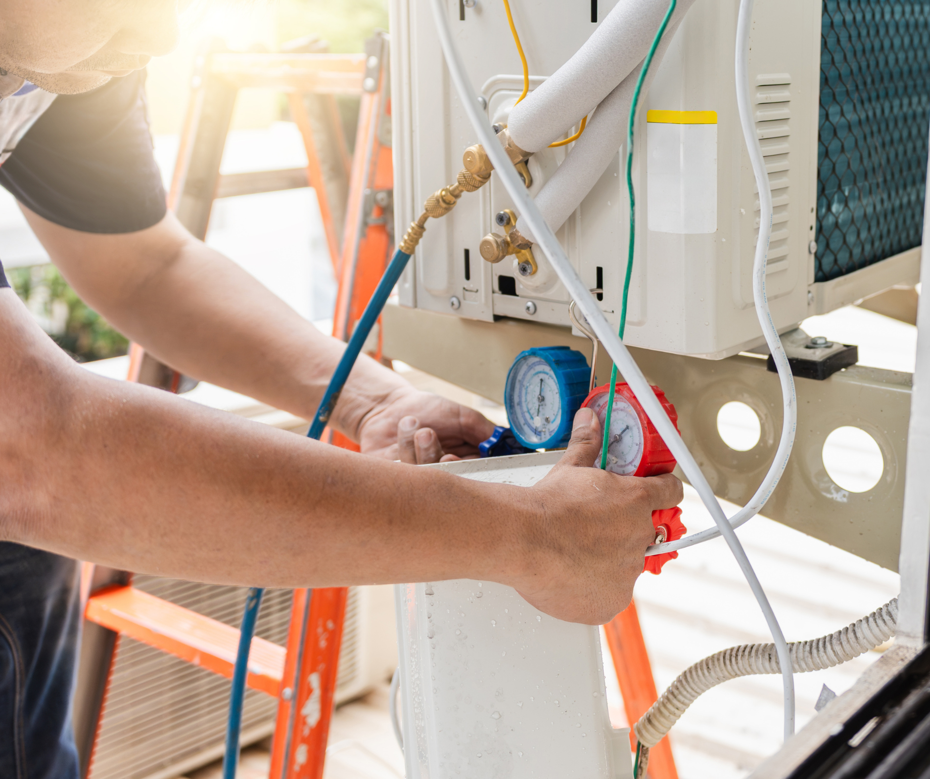 HVAC technician using gauges on an air conditioning unit; outdoors, repairing.
