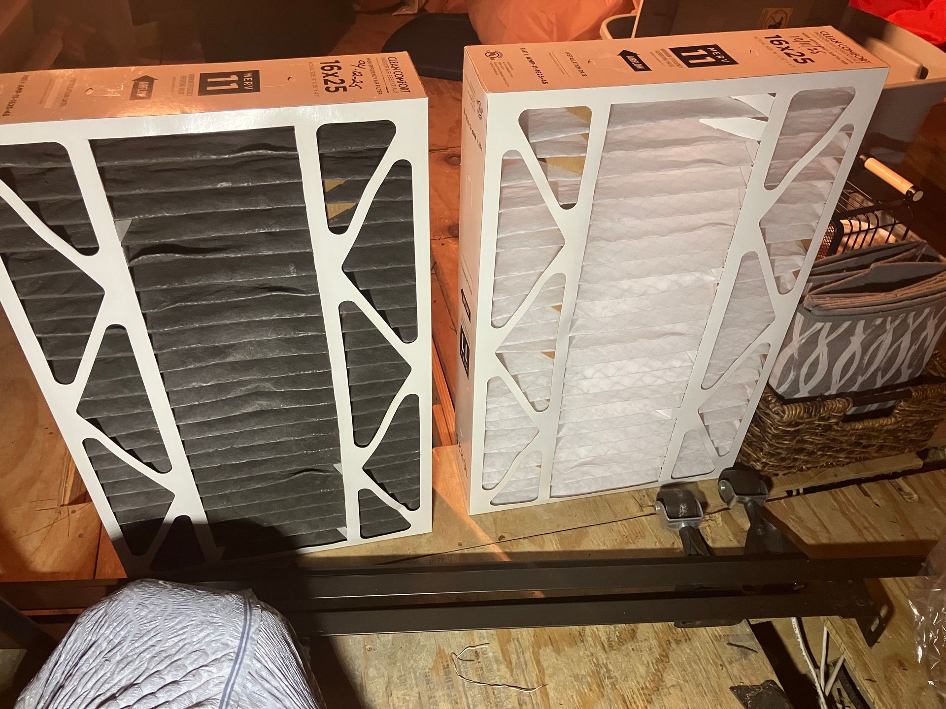 Two air filters: one dirty, black; one clean, white, side-by-side on a wooden surface.
