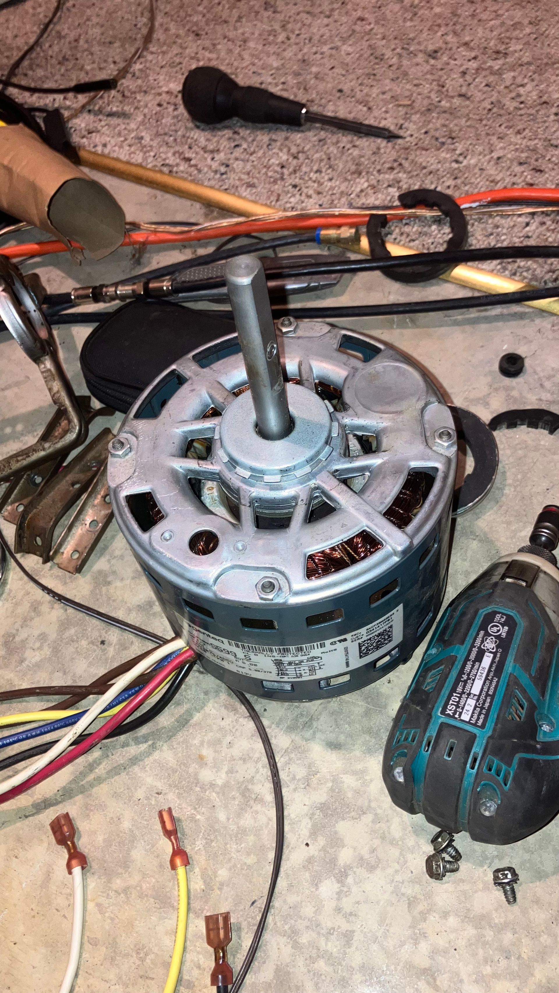 Electric motor with colored wires, on a concrete floor next to tools.