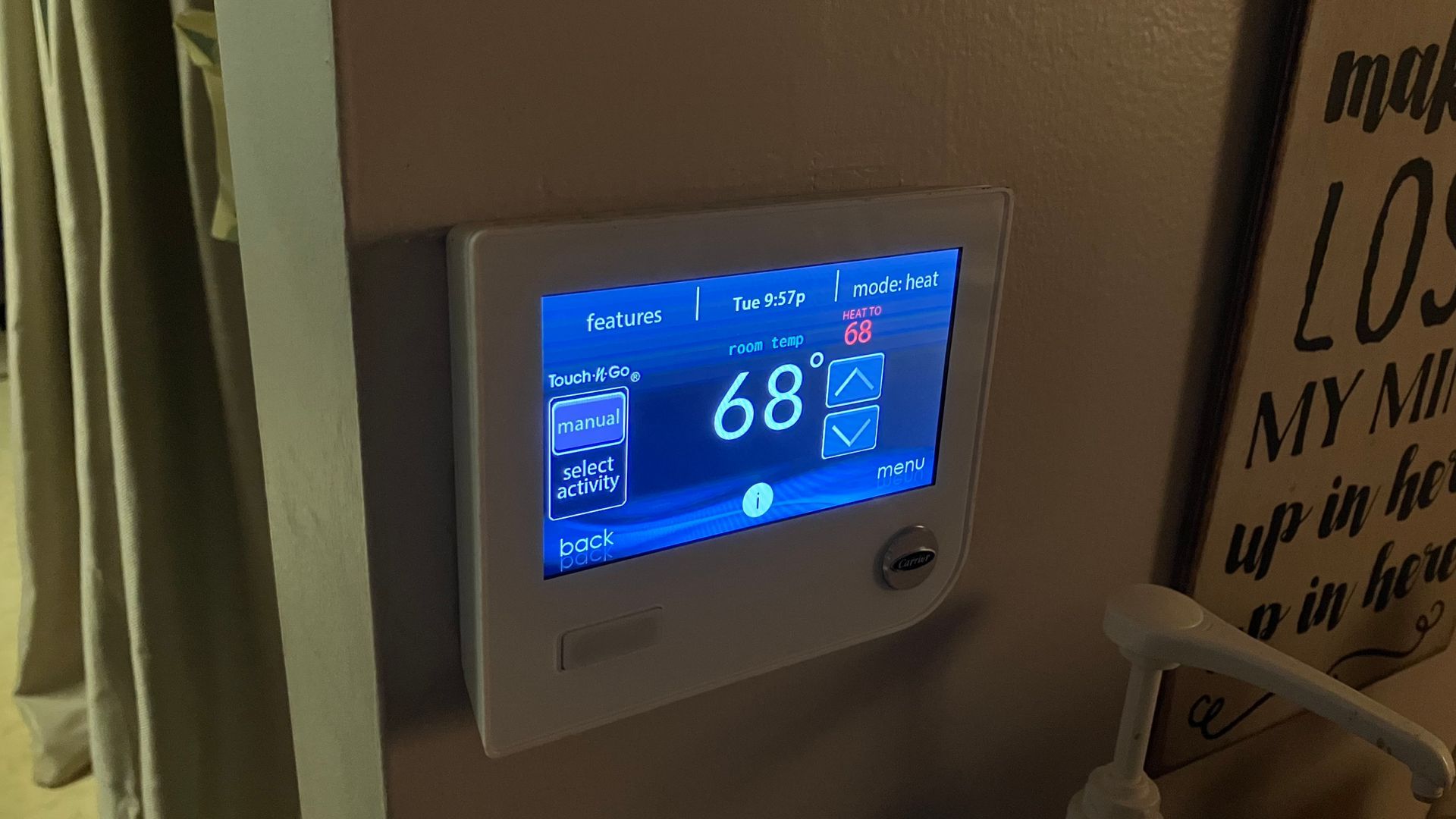 White smart thermostat on wall displays temperature: 68 degrees.