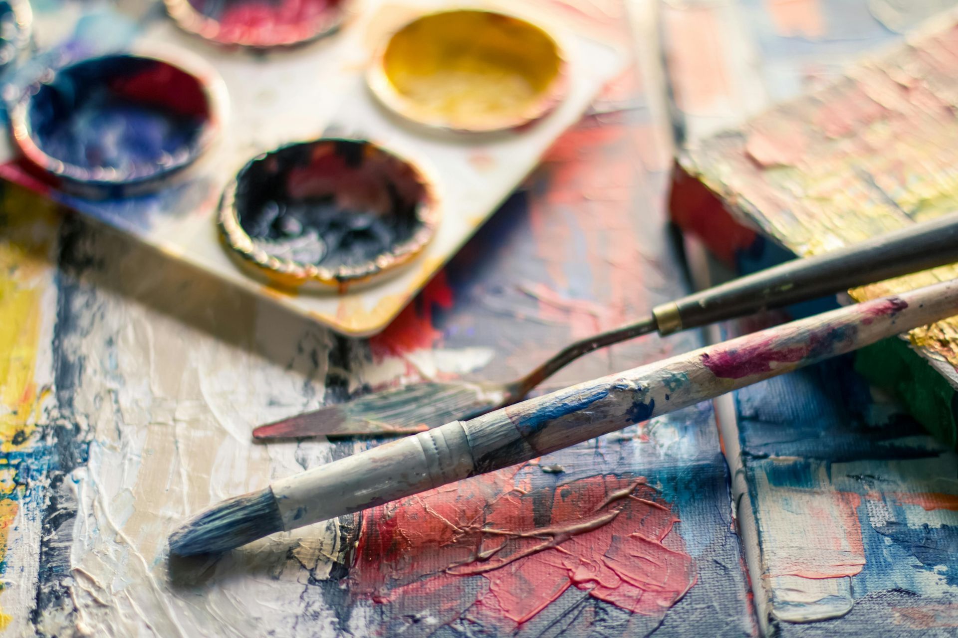 A close up of a palette of paint and a brush on a table.