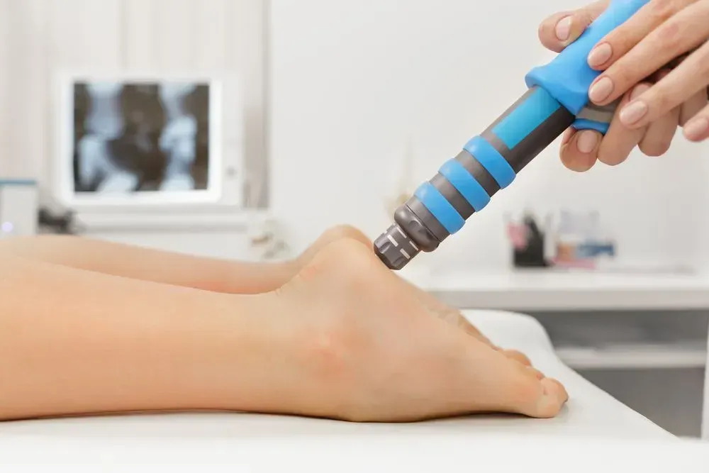 Physical Therapy Device Massaging a Person’s Ankle on a Treatment Table — Lord Street Podiatry in Port Macquarie, NSW
