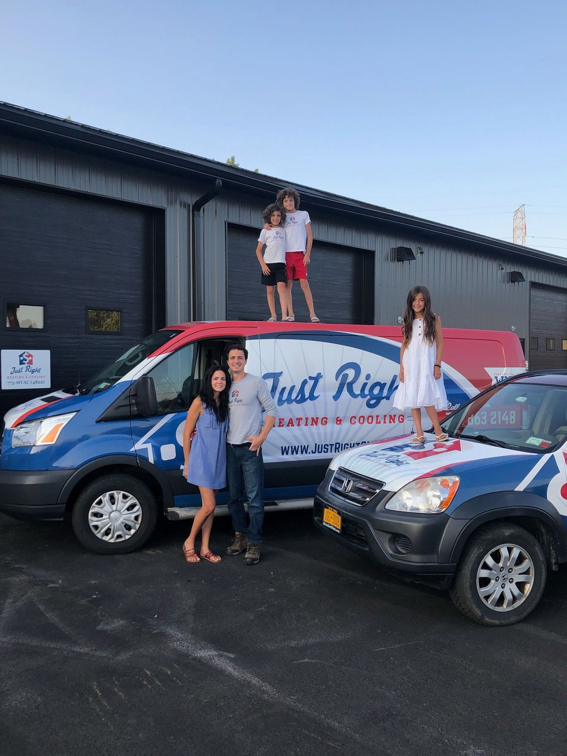 Family posing with Just Right Heating & Cooling vans; children atop van.