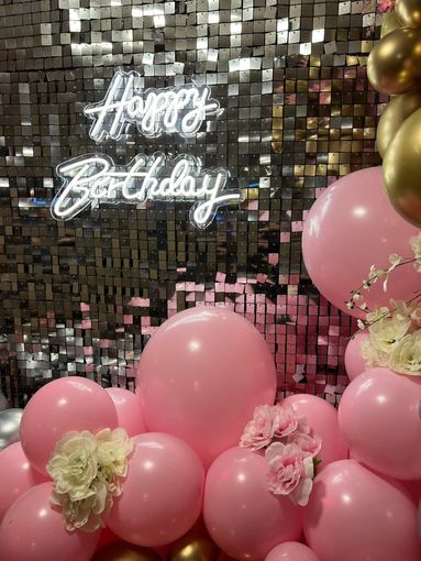 Sweet 16 silver shimmer wall backdrop and pink balloon garland with floral accents. 