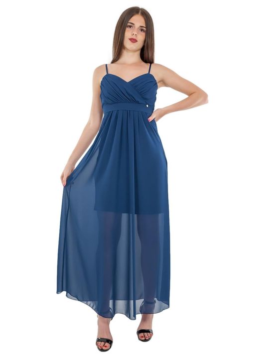 Donna in un abito lungo blu con spalline sottili, in piedi, con in mano l'abito, su sfondo bianco.