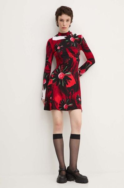 Donna che indossa un abito con stampa floreale rossa e nera, calzini e scarpe nere, in piedi su uno sfondo bianco.