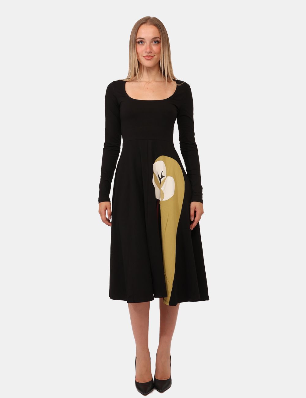 Donna con abito nero a maniche lunghe, decorazione laterale beige e tacchi neri.