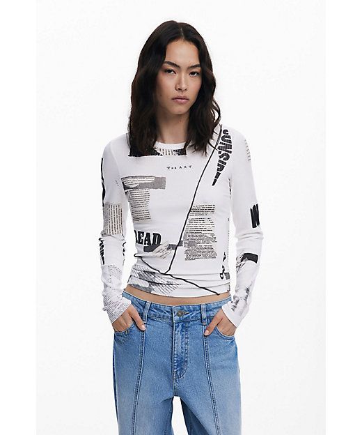 Donna che indossa una camicia bianca a maniche lunghe con stampa di giornale e jeans blu.