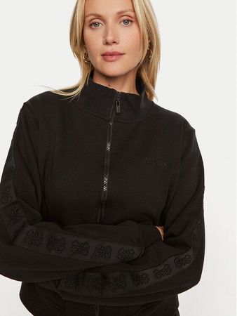 Donna con una felpa nera con cerniera e logo, che guarda la telecamera.