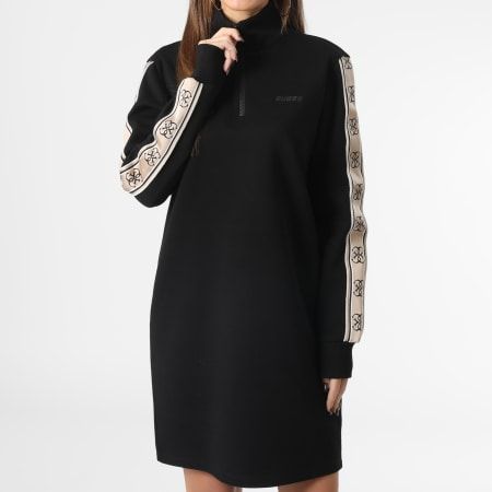 Donna in piedi con abito nero, maniche a fantasia beige e collo alto.