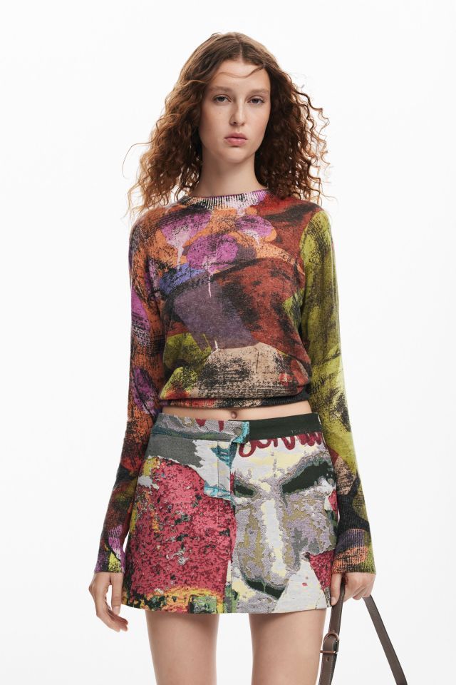 Donna con top e gonna stampati colorati; ambientazione in studio.