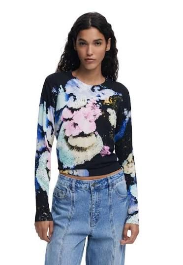 Donna che indossa una maglia a maniche lunghe con stampa floreale e jeans azzurri.