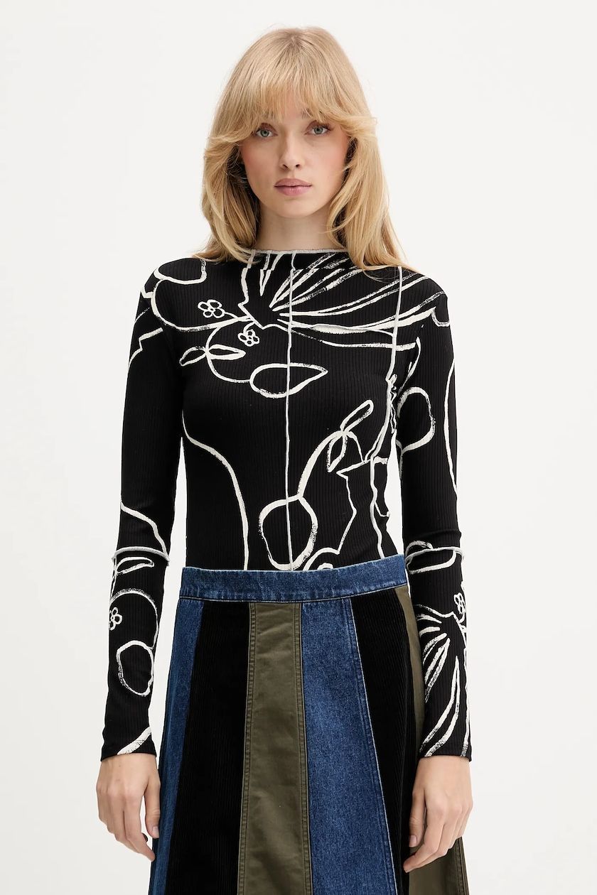 Donna che indossa un top nero a maniche lunghe con fantasia e una gonna di jeans color-block, in piedi davanti a uno sfondo bianco.