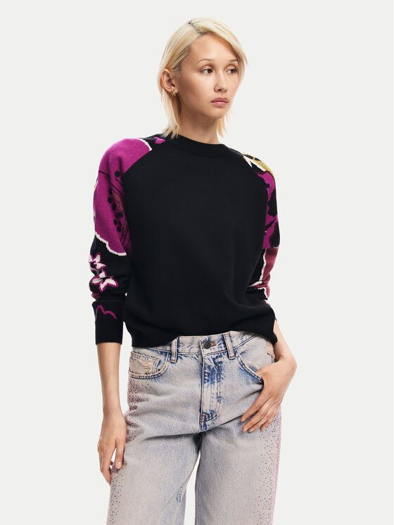 Donna che indossa un maglione nero con maniche fantasia e jeans chiari.