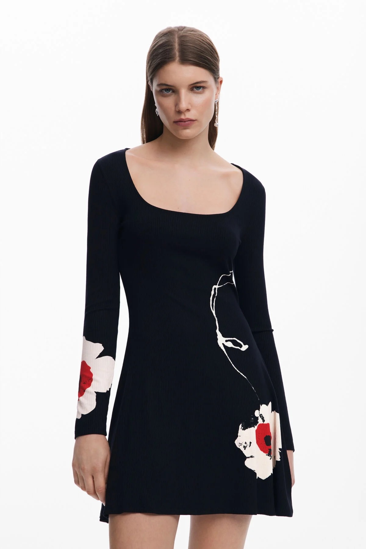 Donna con abito blu navy con motivo floreale bianco e rosso; scollatura a barchetta e maniche lunghe.