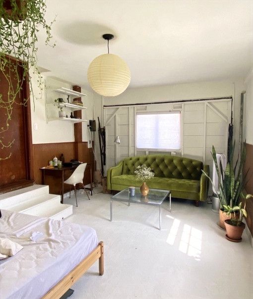 A living room with a green couch and a glass coffee table