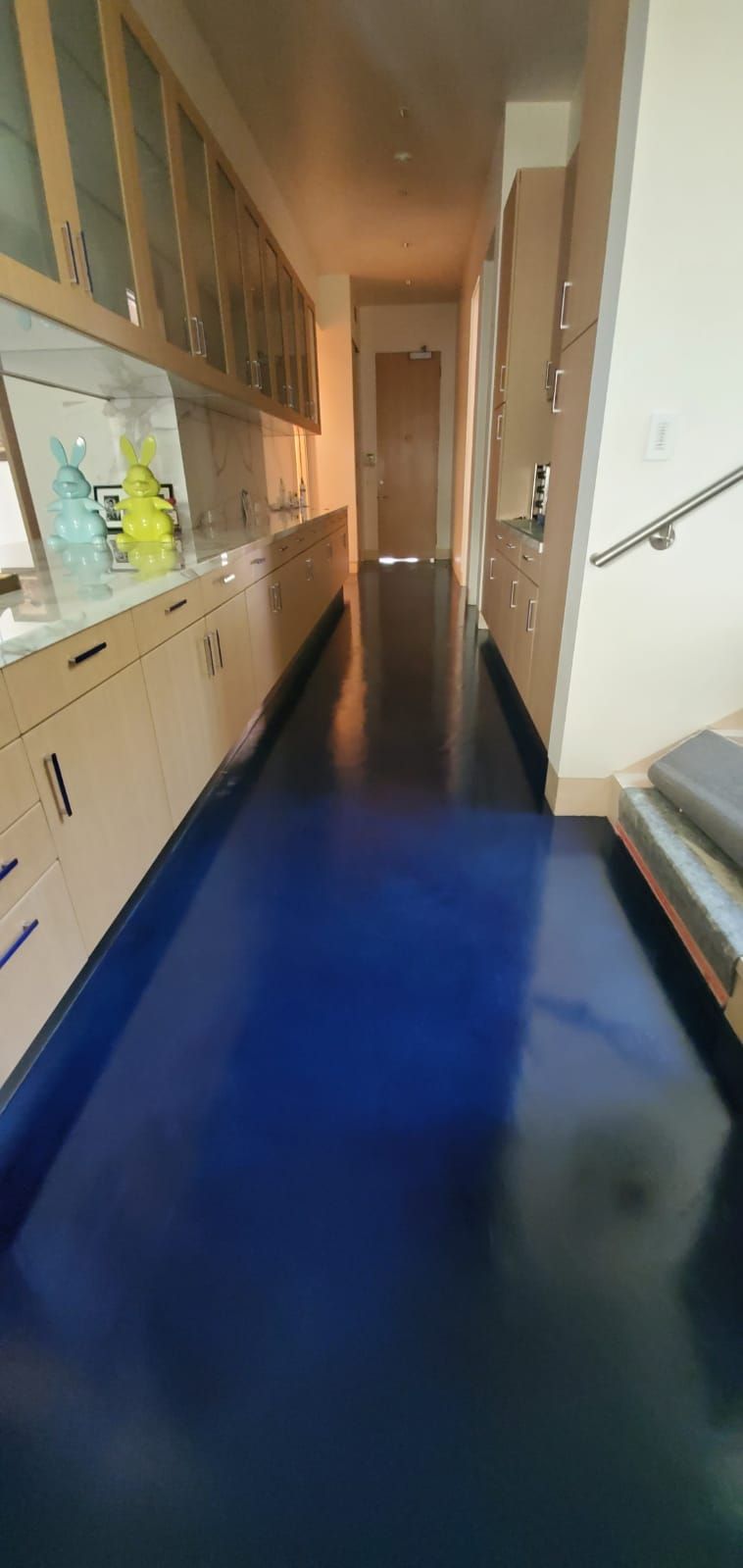 A long hallway with blue floors and cabinets in a kitchen.