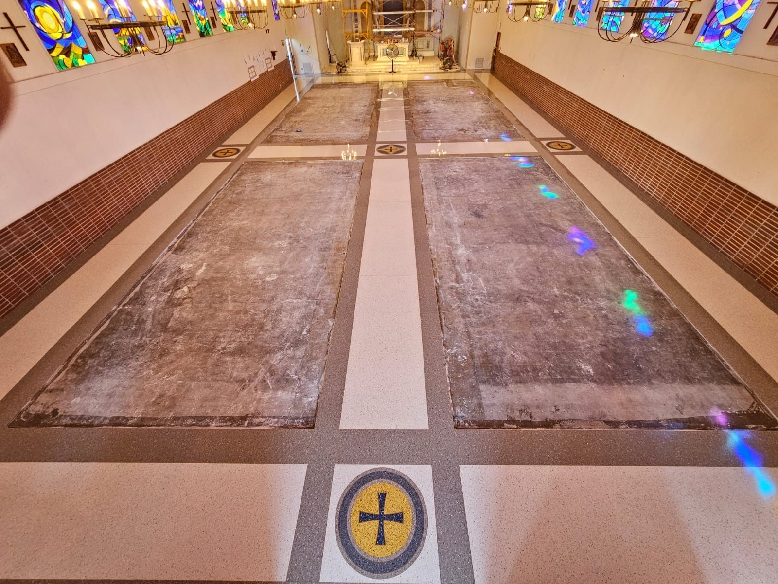 A church with stained glass windows and a cross on the floor
