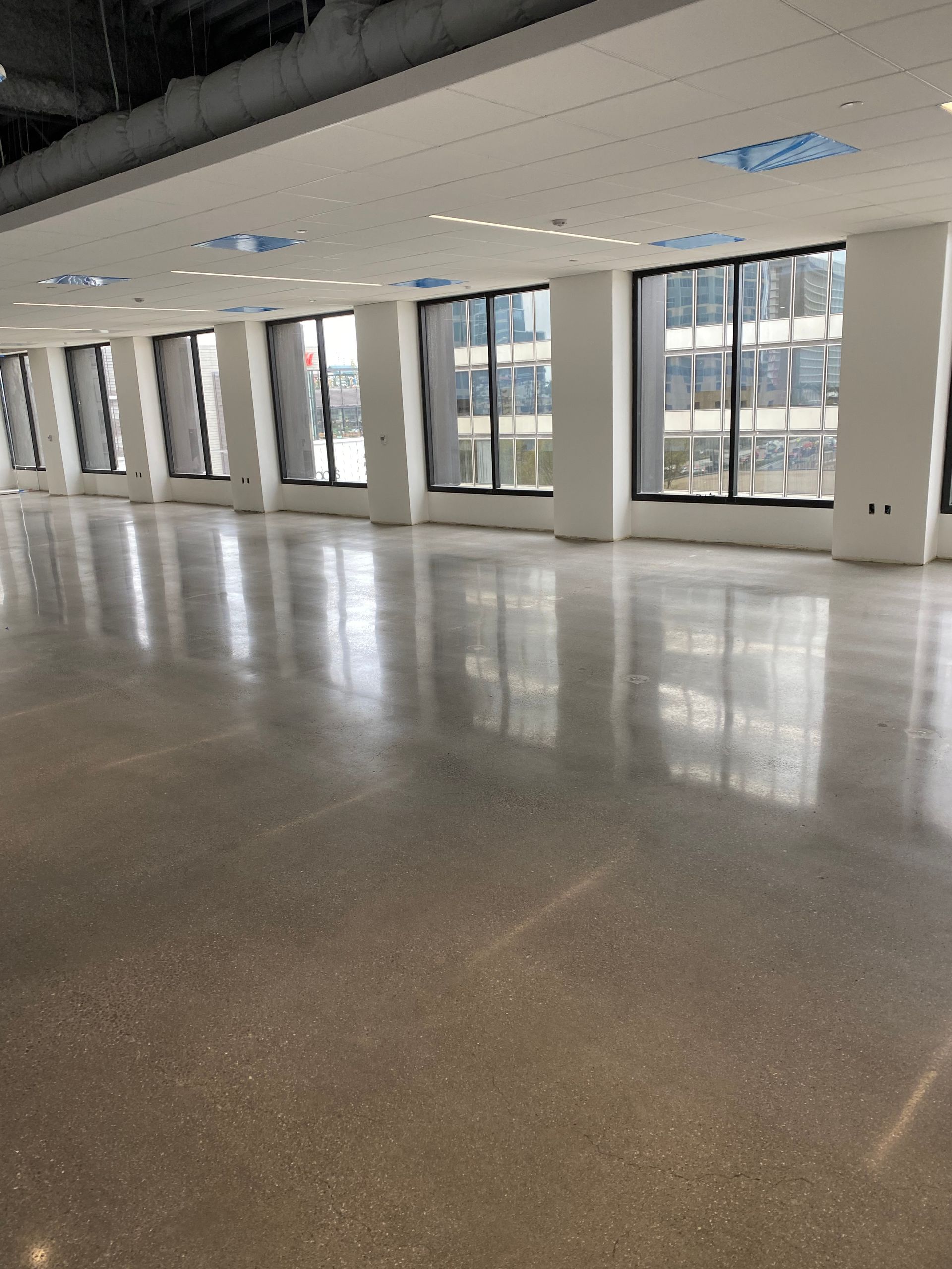 A large empty room with lots of windows and a shiny floor